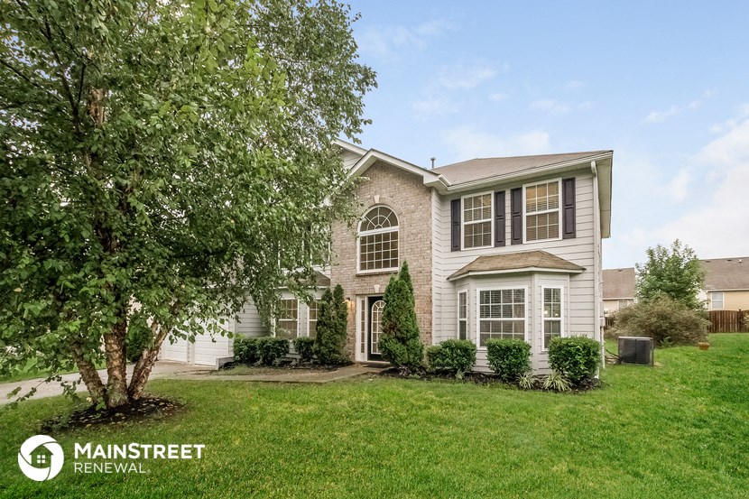 a home with a lawn and a tree in front of it