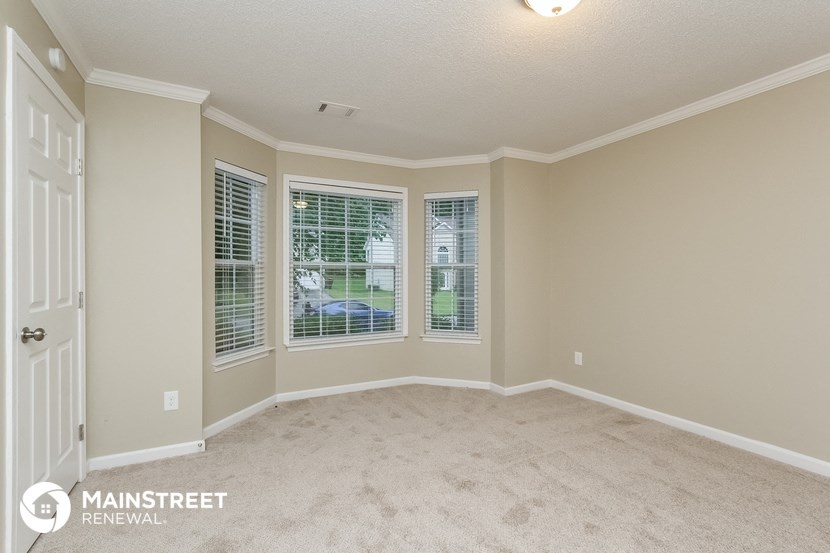 the master bedroom has a large window and carpeted flooring
