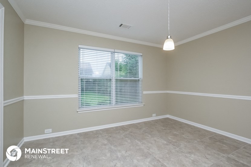 the spacious living room of a house with a large window