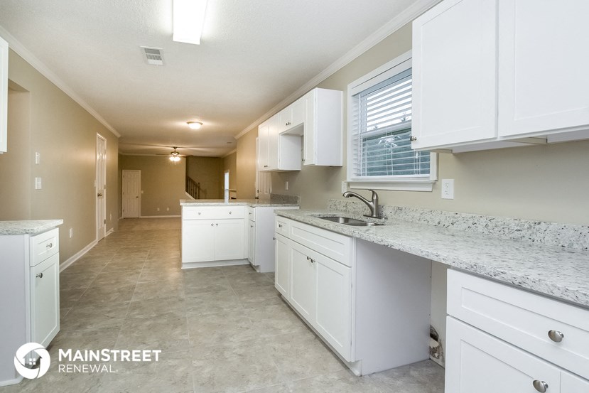 a large kitchen with white cabinets and granite counter tops and a sink