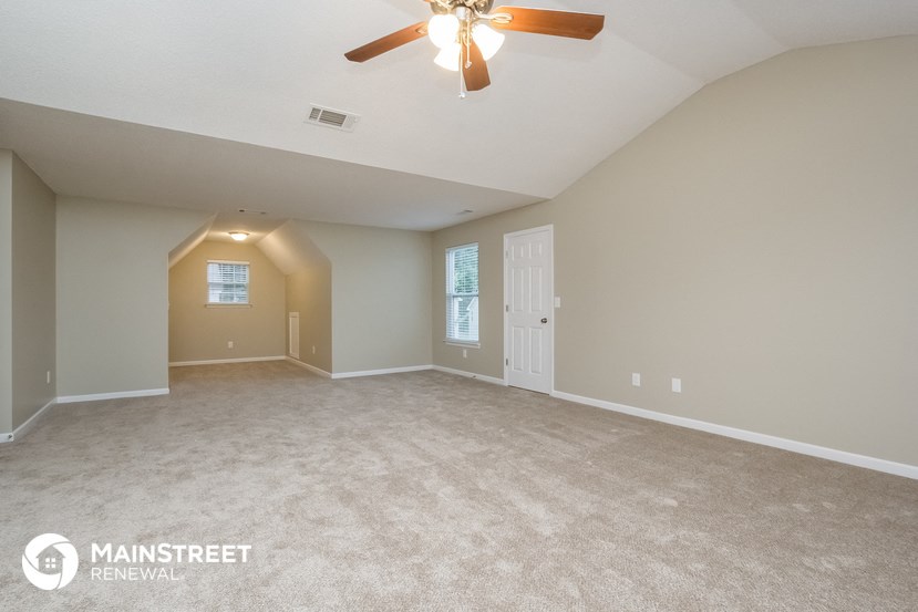 the spacious living room with carpet and ceiling fan