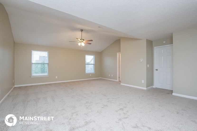 the spacious living room with carpeting and a ceiling fan