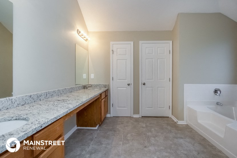 the master bathroom has a large vanity and a tub and a sink