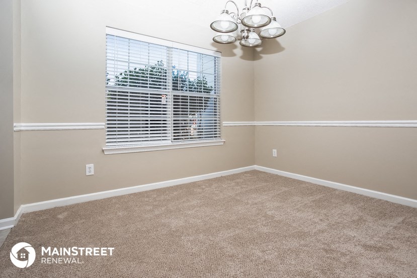 a carpeted room with a window and a chandelier