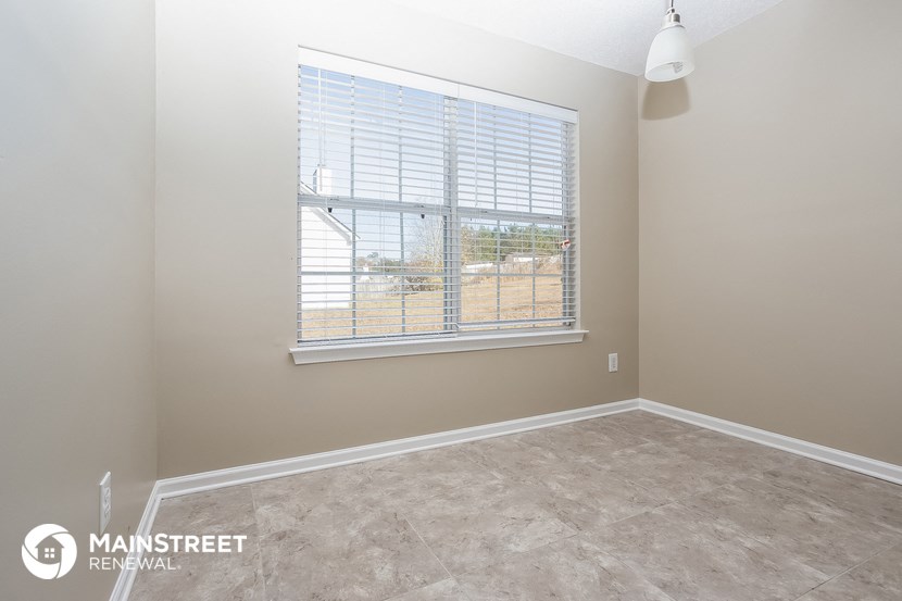 an empty room with a large window with blinds on it