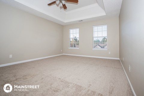 the living room of a new home with carpet and a ceiling fan