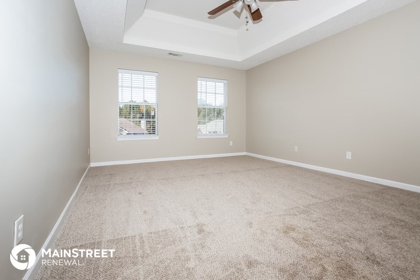 the spacious living room with carpeting and a ceiling fan