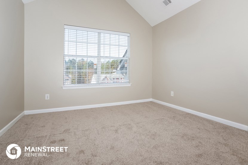 the spacious living room with a large window and carpeted flooring