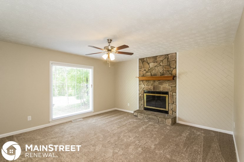 a living room with a fireplace and a ceiling fan