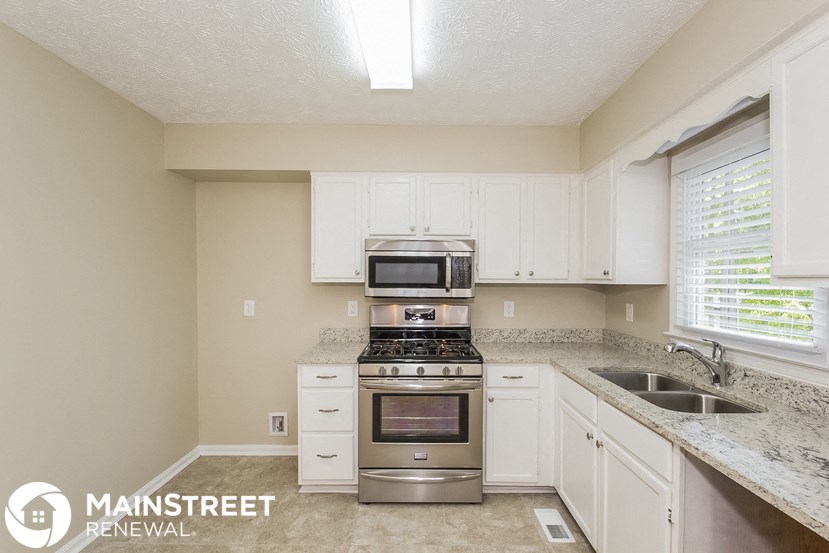 a kitchen with white cabinets and granite counter tops and stainless steel appliances