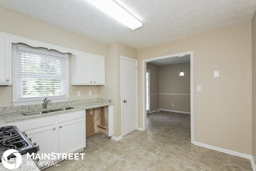 a kitchen with white cabinets and a sink and a door to a hallway