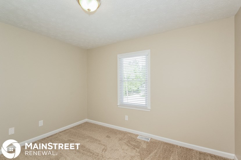 a bedroom with a carpeted floor and a window
