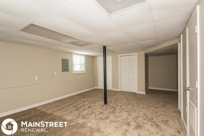 the spacious living room of this manufactured home has carpeted flooring and white walls