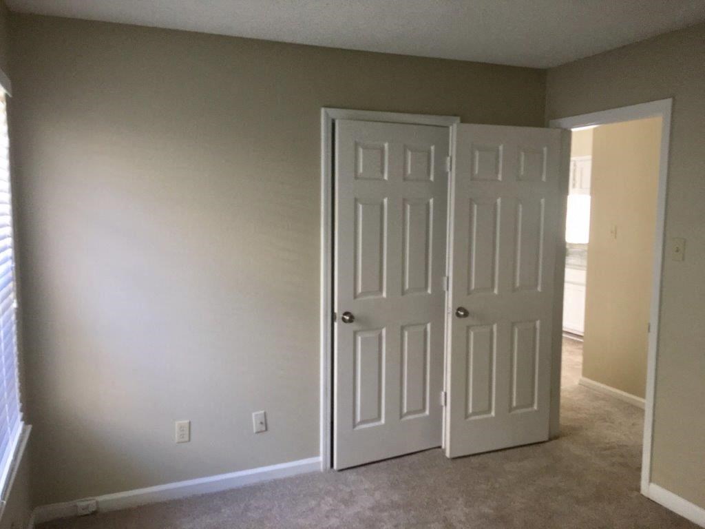 an empty room with two doors and a carpeted floor