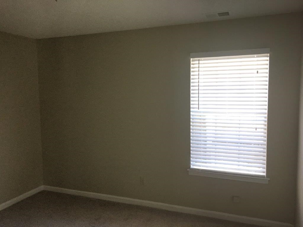 an empty room with a window and white walls