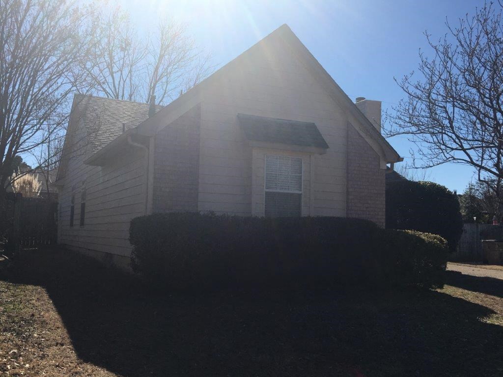 the front of a white house with the sun shining on it