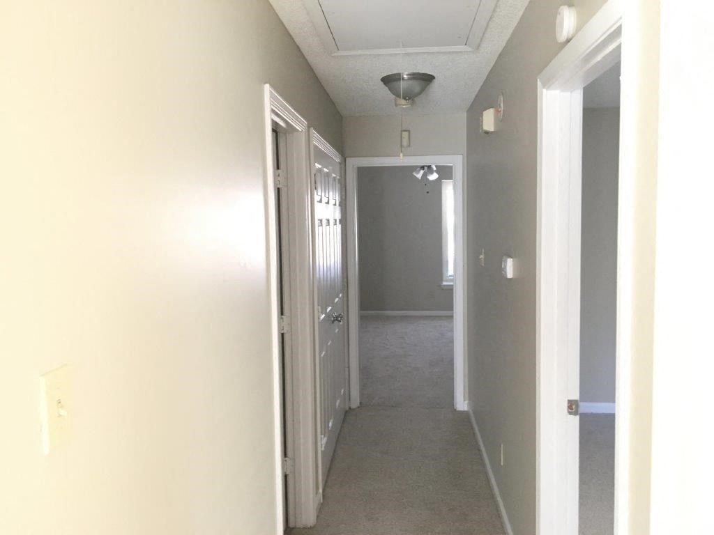 a hallway with white walls and a white ceiling and a door
