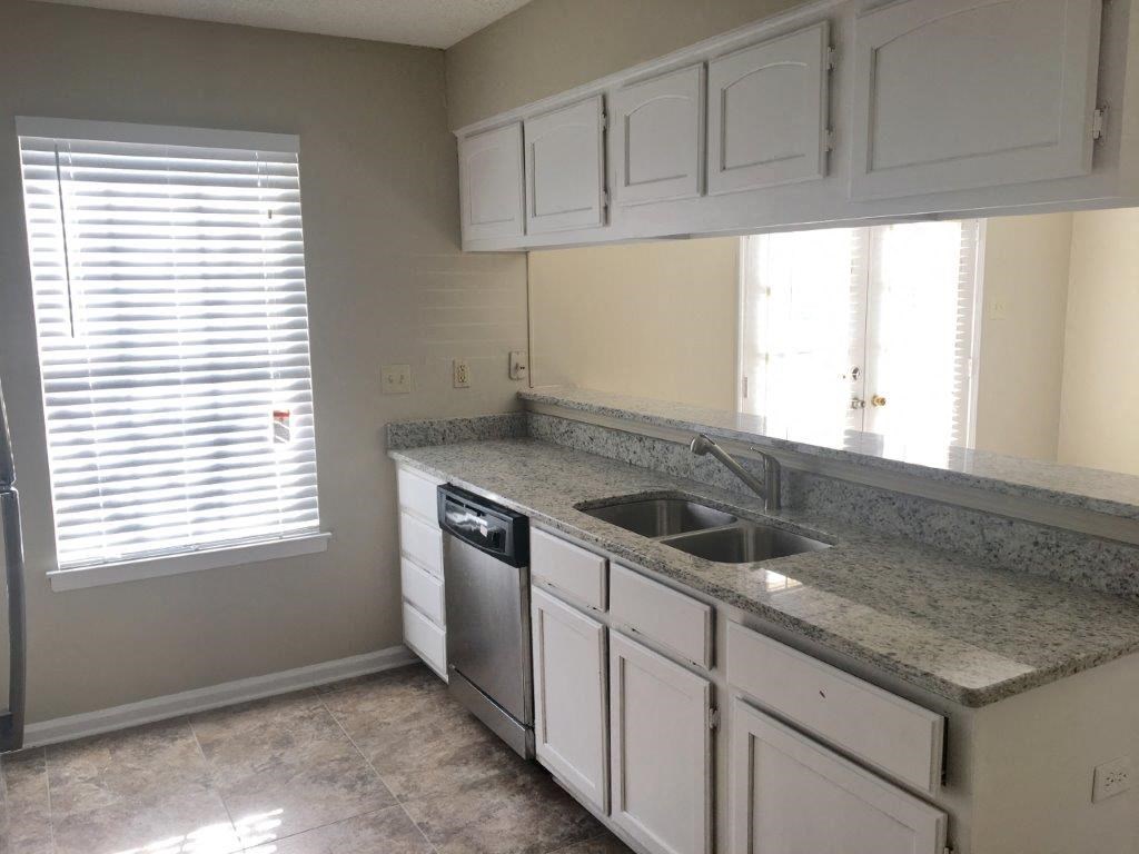 a kitchen with white cabinets and a sink and a window