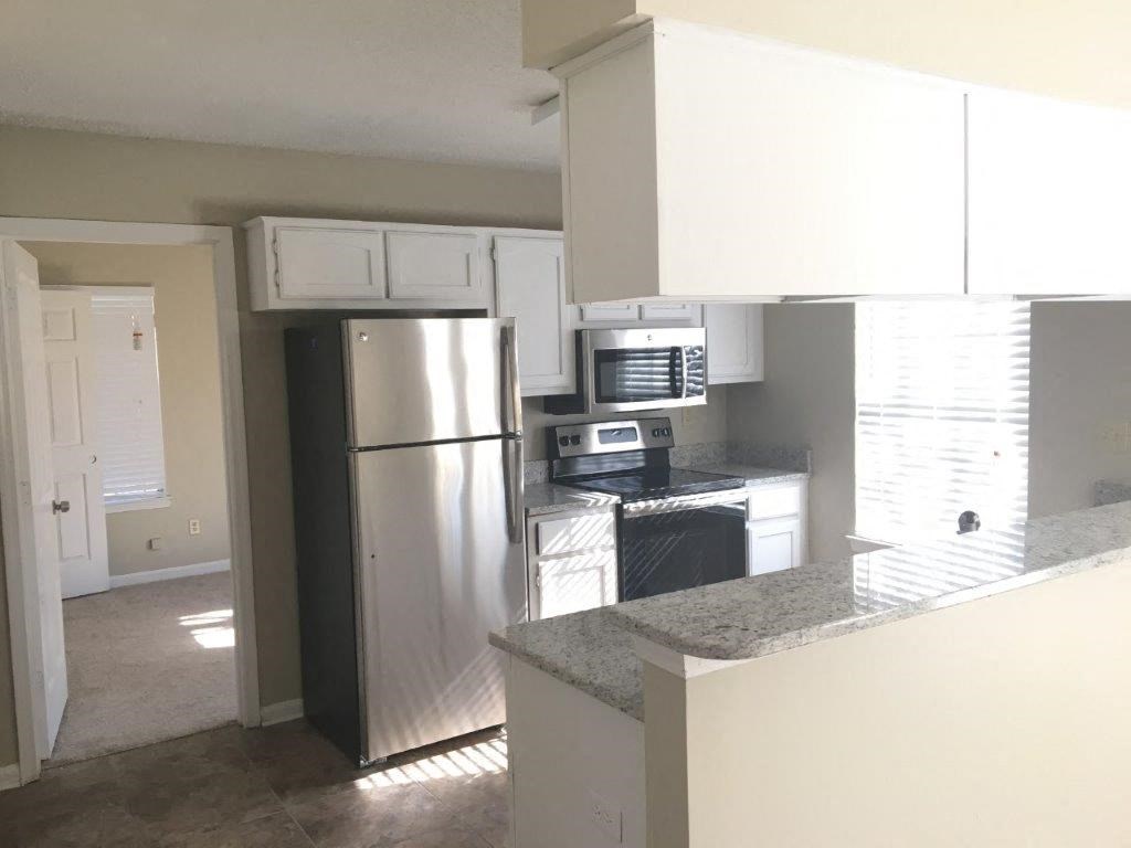 a kitchen with white cabinets and a stainless steel refrigerator