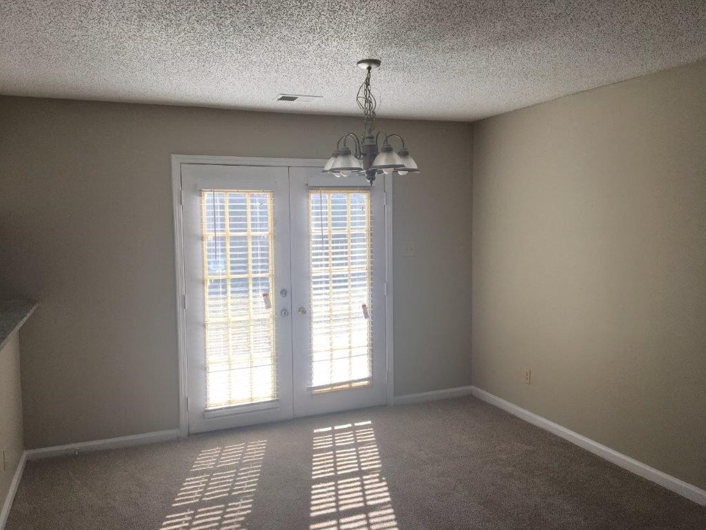 an empty living room with doors and a chandelier