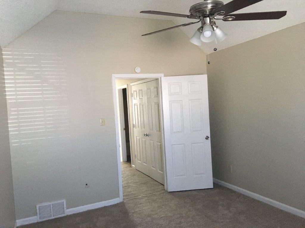 a room with a ceiling fan and a door to a closet
