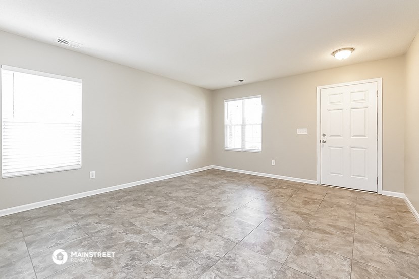 the spacious living room with tile flooring and a white door