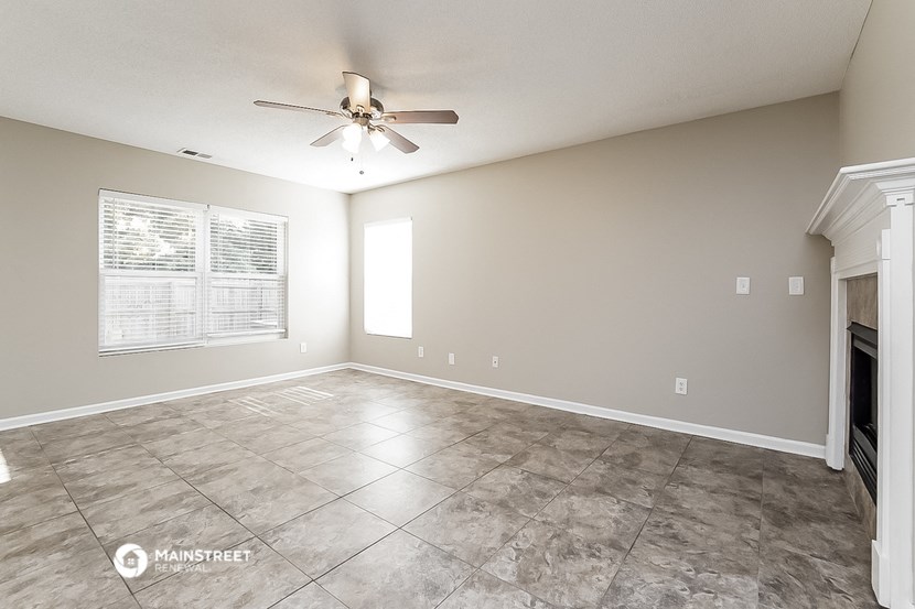 the spacious living room has a fireplace and a ceiling fan