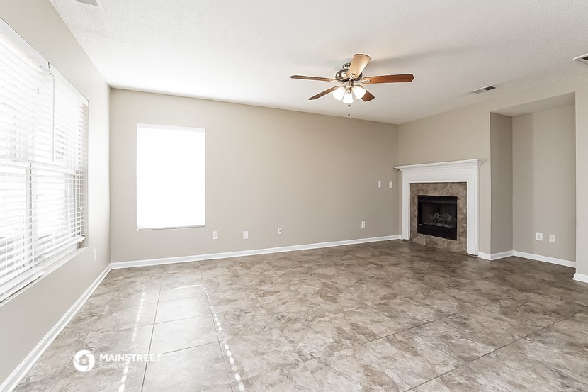 an empty living room with a ceiling fan and a fireplace