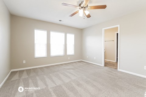 the spacious living room with carpet and a ceiling fan