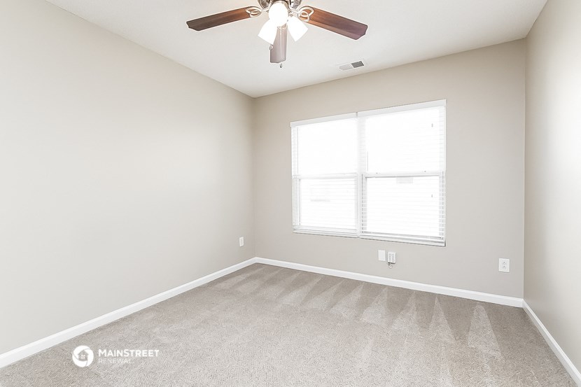 an empty room with a ceiling fan and a window