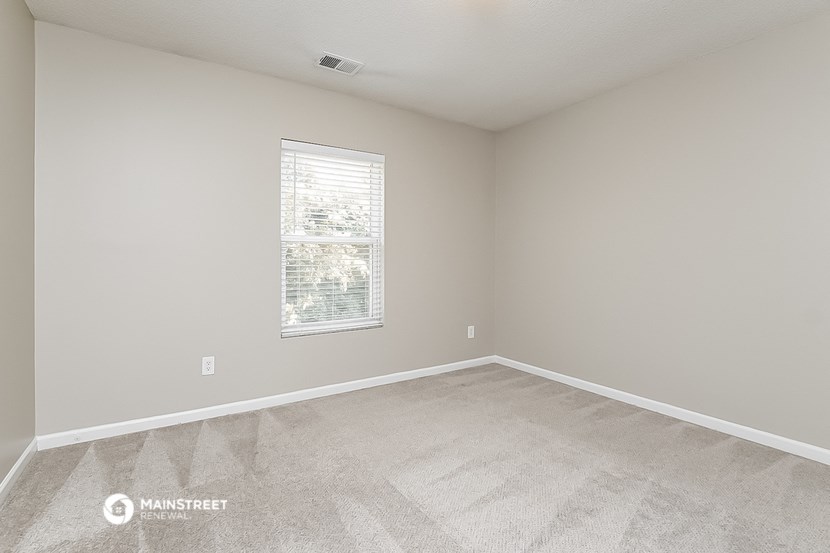 the spacious living room of a manufactured home with carpeting and a window