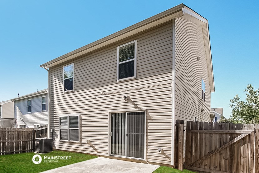 the back of a house with a wooden fence and a yard