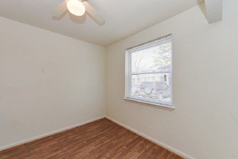an empty room with a window and a ceiling fan