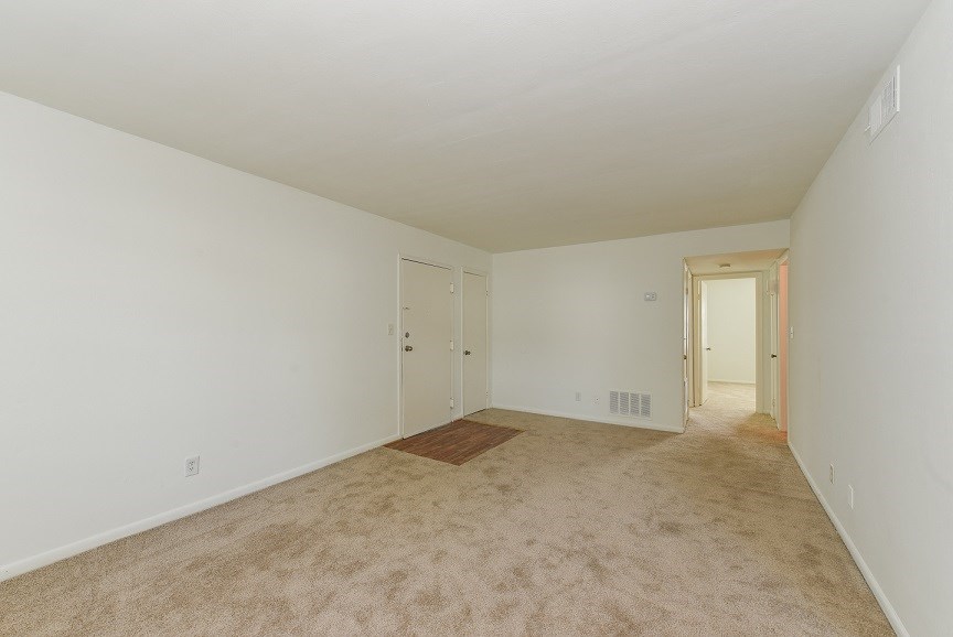 a spacious living room with carpet and white walls