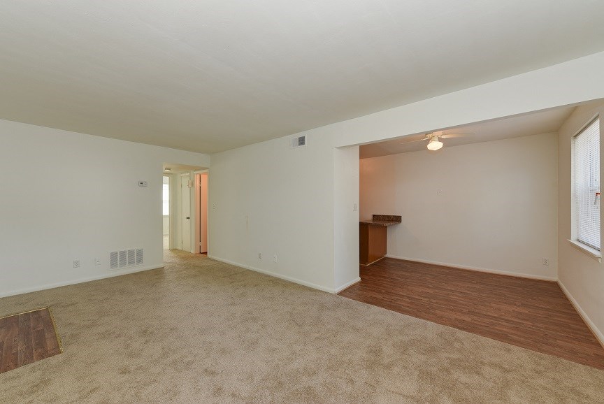 the living room and dining room of an empty home with a hard wood flooring