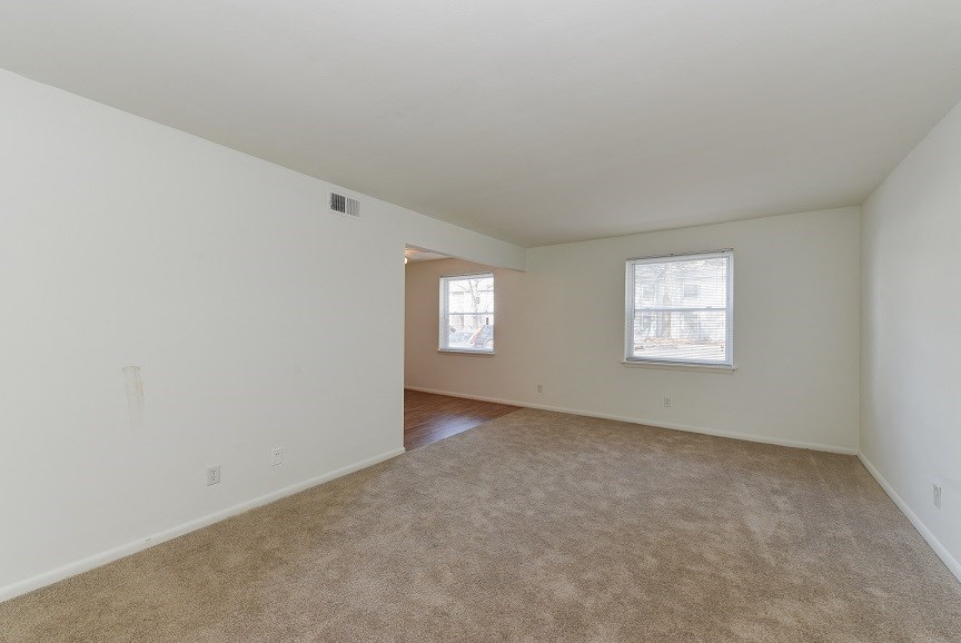 an empty living room with carpet and a window
