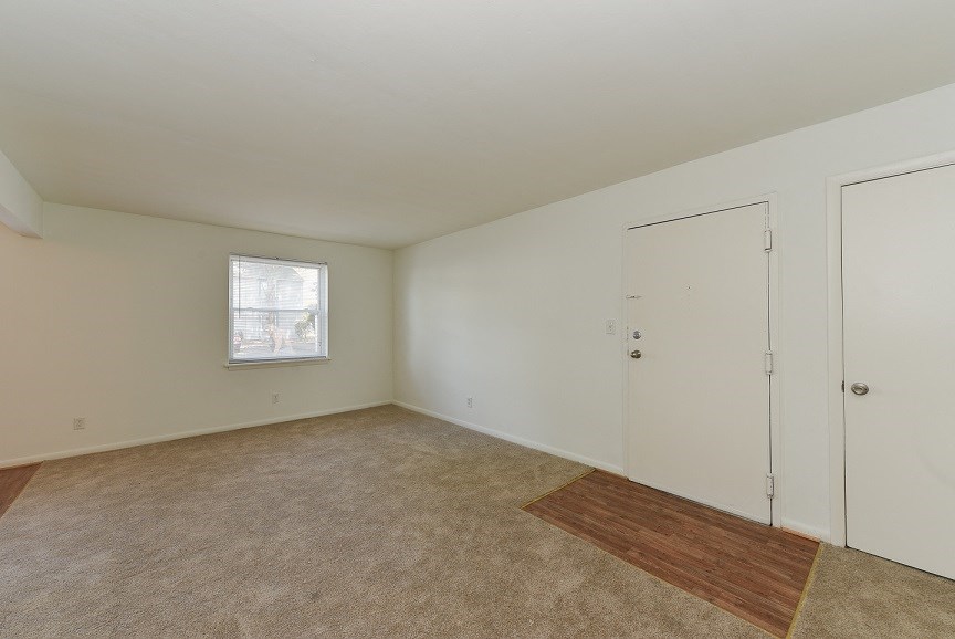 an empty living room with white walls and a window and a door