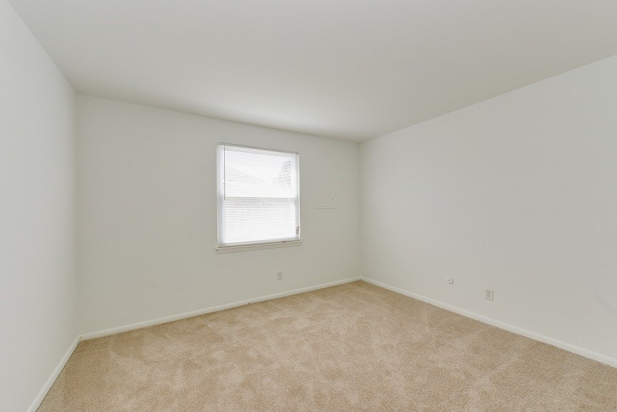 an empty room with a window and carpeting