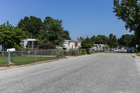 A street with a fence and trees on the side.