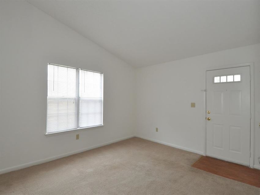 the living room of an empty bedroom with a white door and window