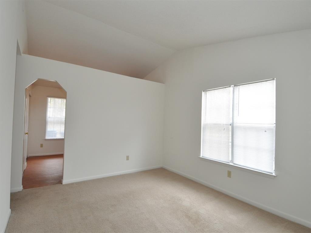 an empty living room with white walls and a window