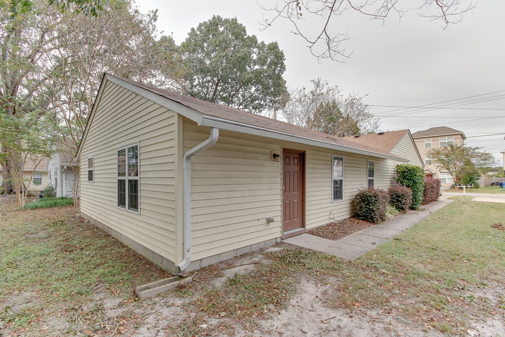 a small tan house with a brown door and a sidewalk