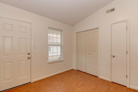 a bedroom with two closets and a window and a wood floor