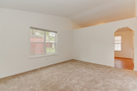an empty living room with carpet and a window
