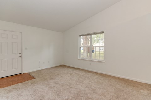 an empty living room with white walls and a window