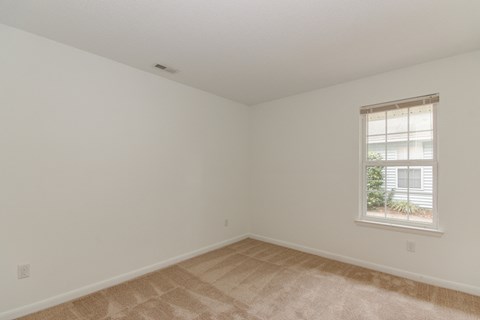 a bedroom with white walls and a window