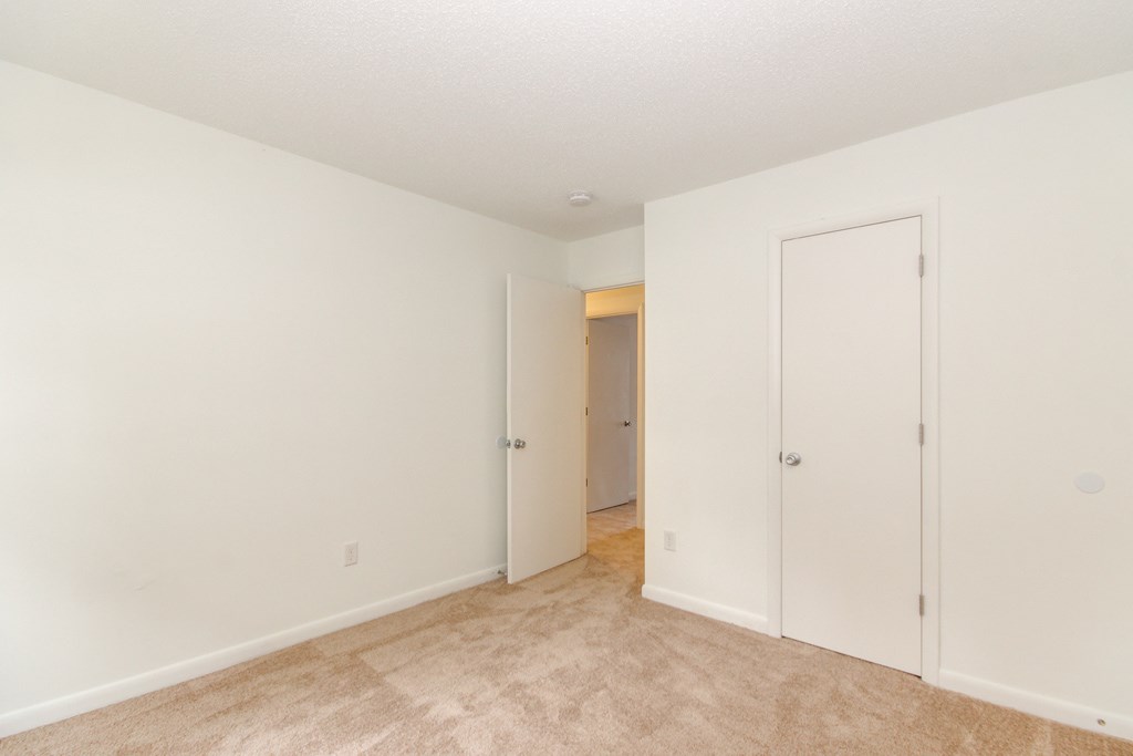 a bedroom with white walls and a door to a closet