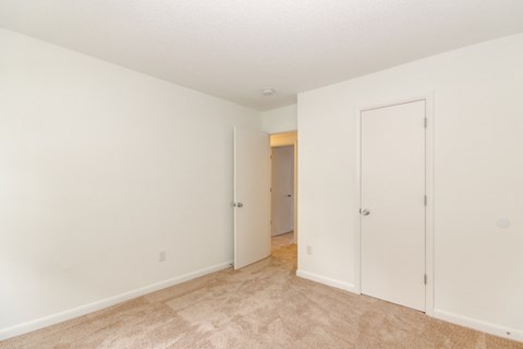 a bedroom with white walls and a door to a closet