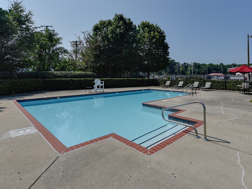 a swimming pool with chairs and a fence around it