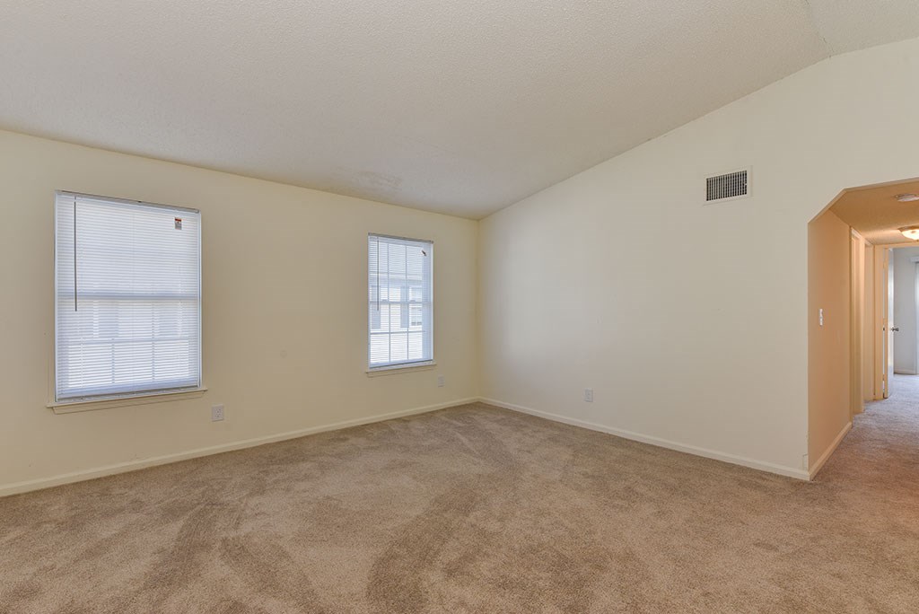 the living room and dining room of an empty home with carpeting